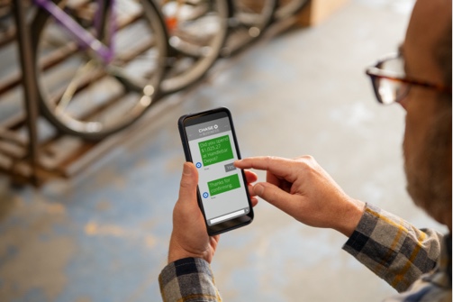 Bike shop owner messages on smartphone