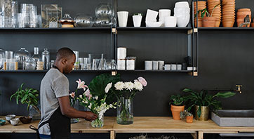 A shop owner sets up a flower arrangement