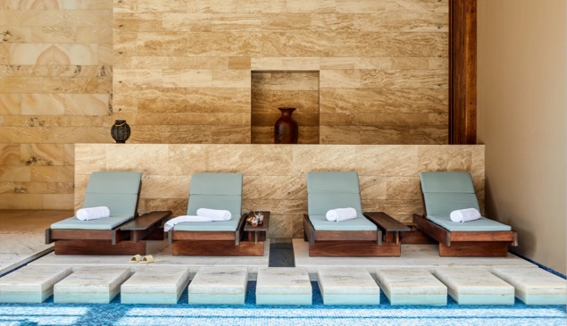 Four reclining chairs sit alongside a luxurious indoor pool