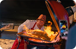 Chef Emeril Lagasse cooking a fish on the beach during the Barefoot BBQ