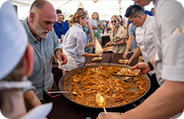 Chef José Andrés serving his signature paella out of an oversized frying pan, prepared beachside for cardmembers 