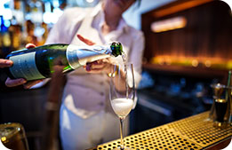 A close-up shot of a server pouring a glass of champagne
