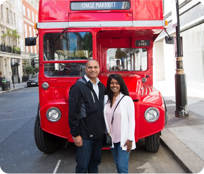Cardmembers pose in front of a red double decker bus
