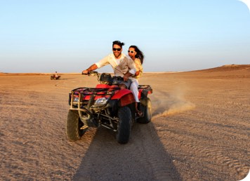 A couple riding a dune buggy together through the desert
