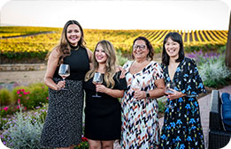 A group of Marriott Bonvoy Cardmembers pose with their wine glasses in front of the vineyard
