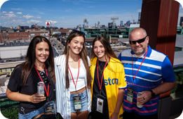 Guests smile for the camera in front of the Boston skyline