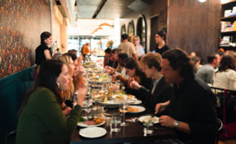 A large group enjoy a meal seated at a long restaurant table