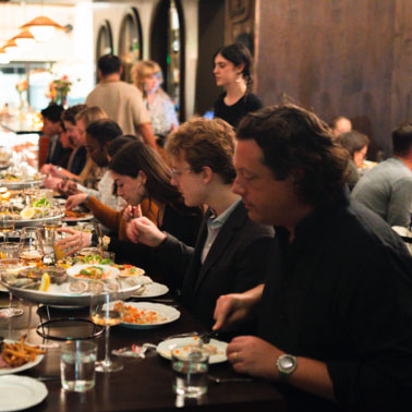 A large group enjoy a meal seated at a long restaurant table