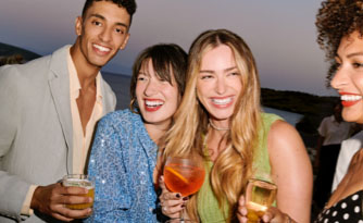 A candid photo of guests holding cocktail glasses smiling and enjoying themselves outdoors