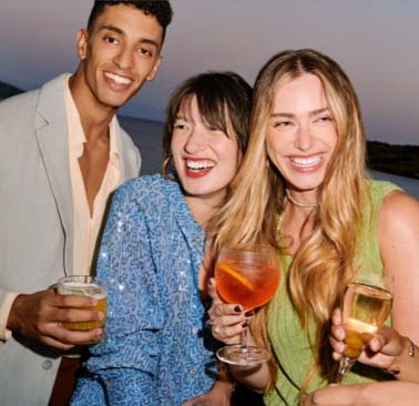 A candid photo of guests holding cocktail glasses smiling and enjoying themselves outdoors