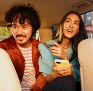 A woman on her phone sitting in the back of a rideshare car with a man