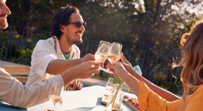 Friends get together outdoors and toast their wine glasses