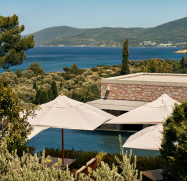 Luxury resort in Turkey with umbrellas, pool, greenery, and sea view.