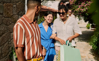 A group of friends walking down a brick path carrying bags