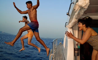 Two men jumping off a boat while woman watches