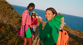 Overlooking the ocean, a group of friends hike up to the top of a mountain