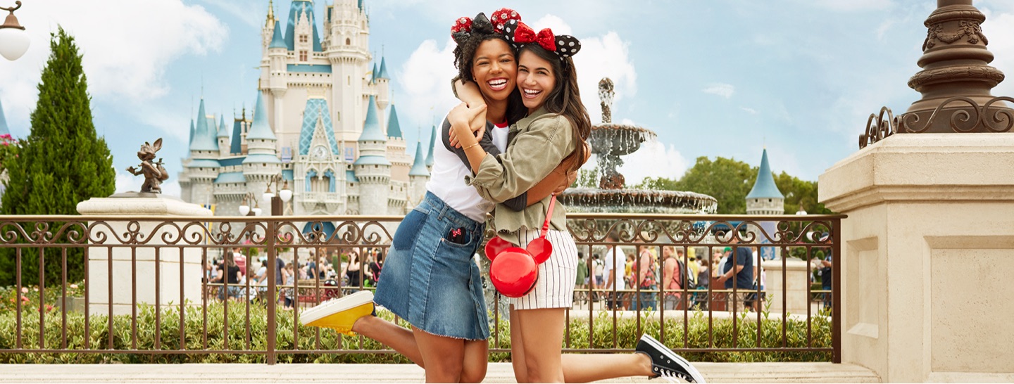 Two girls hugging in front of a Disney Castle