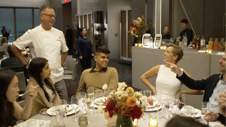 A chef speaks with a group of seated diners