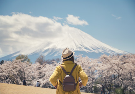 A hiker looking at Mt. Fuji behind cherry blossoms in Tokyo, Japan