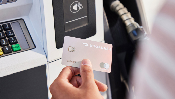 A cardmember uses her DoorDash Credit Card at a gas station pump