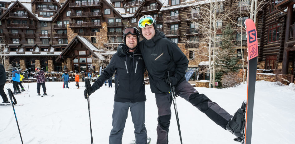 Two skiers pose with one another outside The Ritz-Carlton Bachelor Gulch
