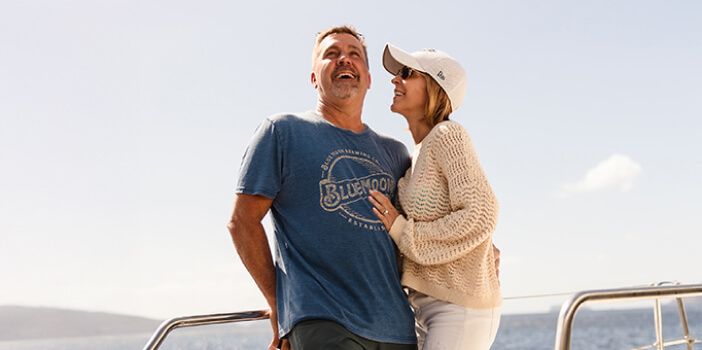 Couple embracing on a balcony with a scenic view of the sea and sunset.