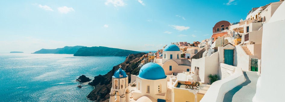 A picturesque view of the iconic blue-domed churches and whitewashed buildings of Oia, Santorini, Greece.