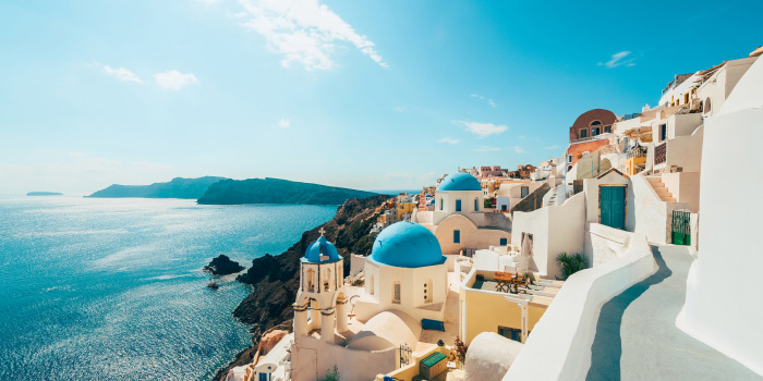 A picturesque view of the iconic blue-domed churches and whitewashed buildings of Oia, Santorini, Greece.