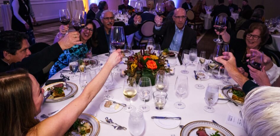 Guests raise their wine glasses for a toast during dinner.