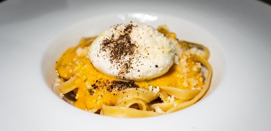 Close-up of freshly plated burrata over pasta.