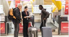 Iberia Airline's gate attendant giving passengers a travel voucher