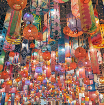 Hundreds of brightly lit multicolored lanterns hanging from a ceiling