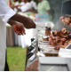 A Caribbean chef cooks chicken over an outdoor grill
