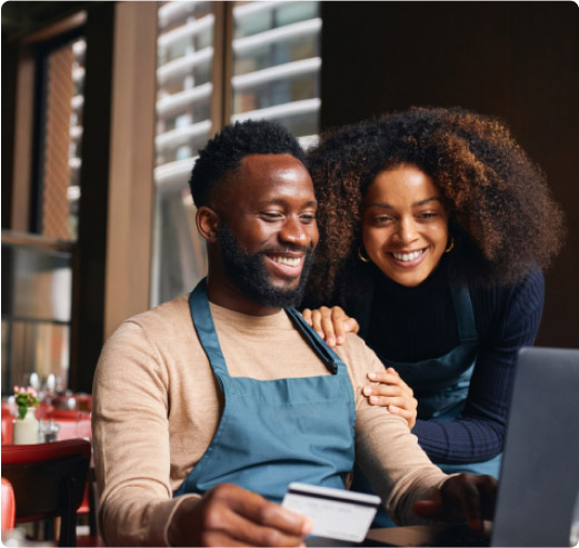 Two small business owners happily make a purchase online with their Ink card