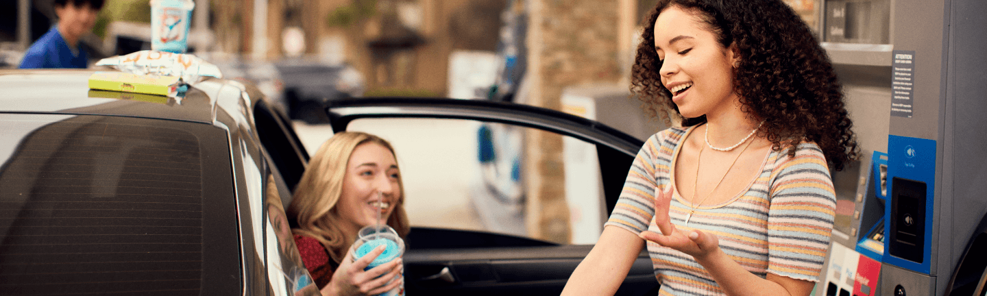 Girl pumping gas with friend