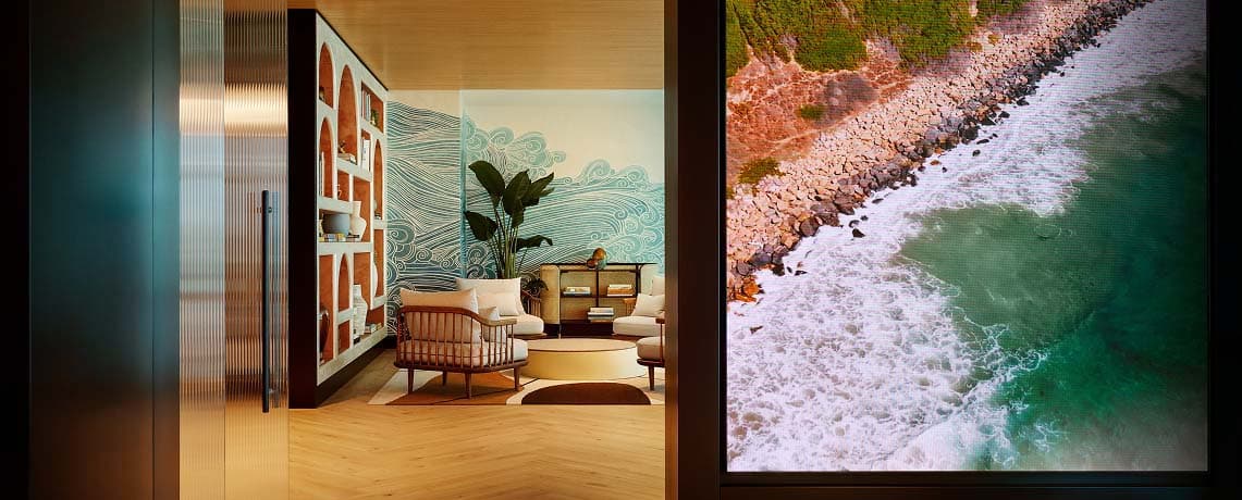 Sapphire Lounge at San Diego International Airport with contemporary furniture and a large mural of ocean waves.