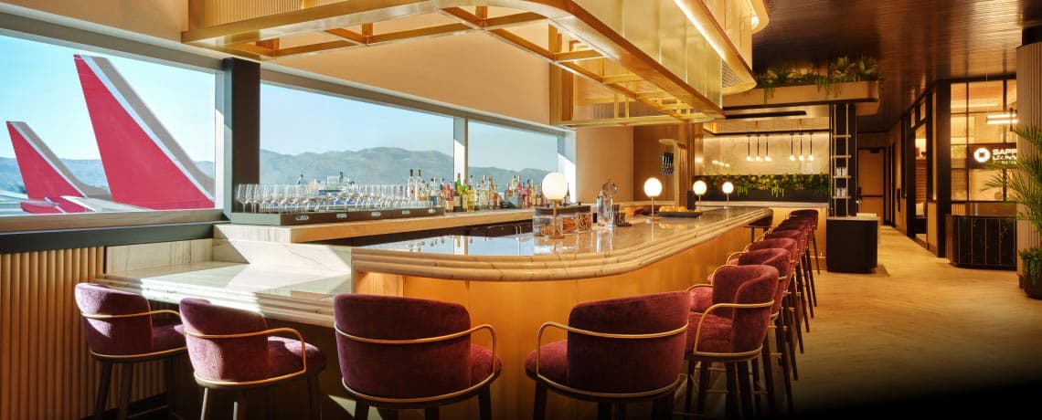 Sapphire Lounge at Phoenix Sky Harbor International Airport with a curved bar counter, purple stools, and large windows with runway views.