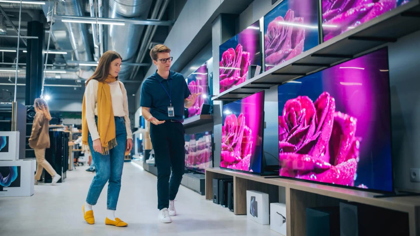 Two people shopping for TVs in an electronics store