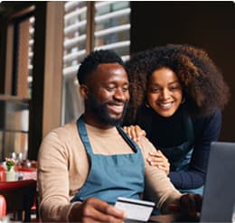 Two small business owners happily make a purchase online with their Ink card