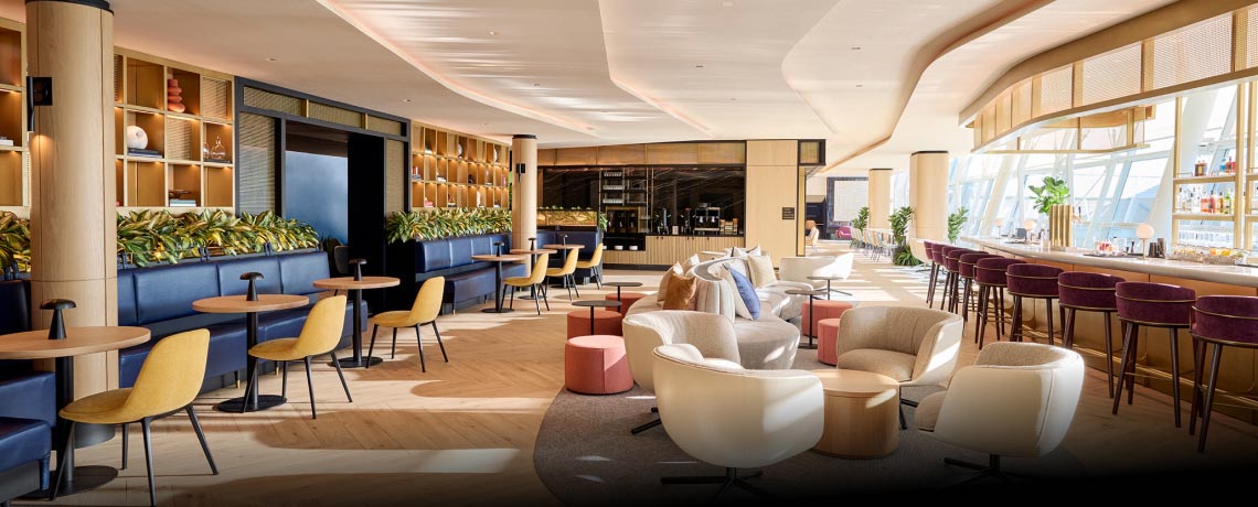 Sapphire Lounge at John F. Kennedy International Airport, New York, with round tables, armchairs, a bar area, and large windows.