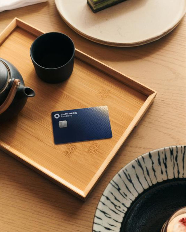A wooden tray on a table with a black teapot, a black cup, and Sapphire Reserve card.