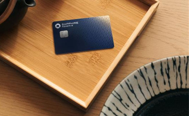 A wooden tray on a table with a black teapot, a black cup, and Sapphire Reserve card.
