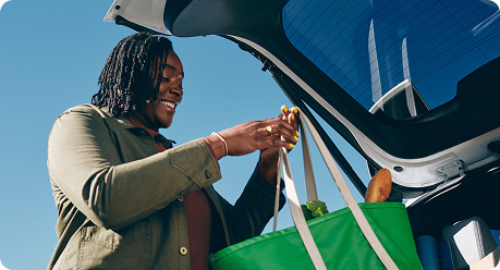 Woman taking a grocery bag out of the car 