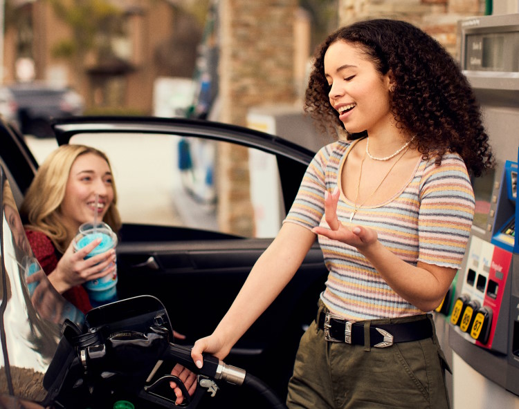 Girl pumping gas with friend