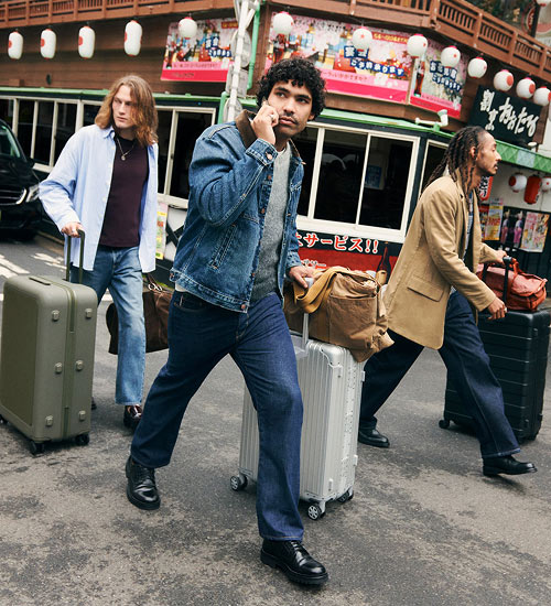 Three men walking in the street with suitcases