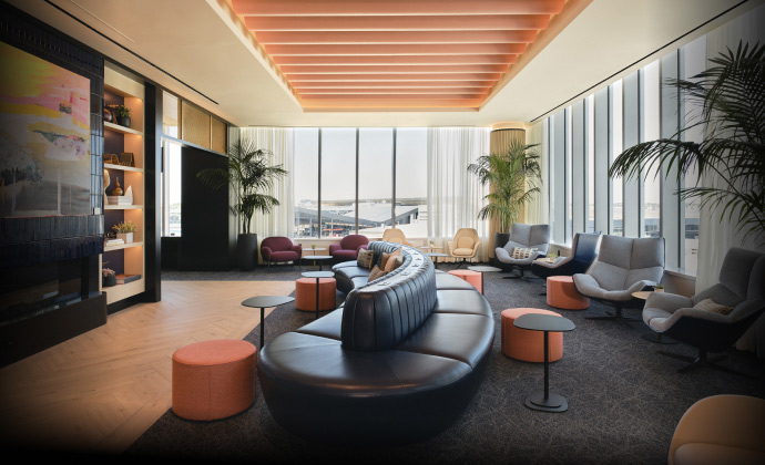 Modern Sapphire Lounge at Boston Logan International Airport with curved leather sofas, armchairs, small tables, and large windows with runway views.