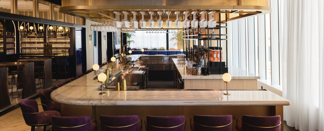Modern Sapphire Lounge at Boston Logan International Airport with curved leather sofas, armchairs, small tables, and large windows with runway views.
