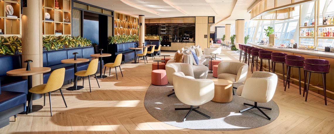 Sapphire Lounge at John F. Kennedy International Airport, New York, with round tables, armchairs, a bar area, and large windows.