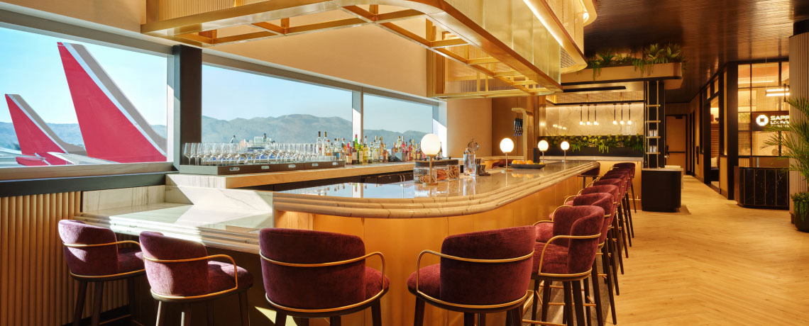 Sapphire Lounge at Phoenix Sky Harbor International Airport with a curved bar counter, purple stools, and large windows with runway views.