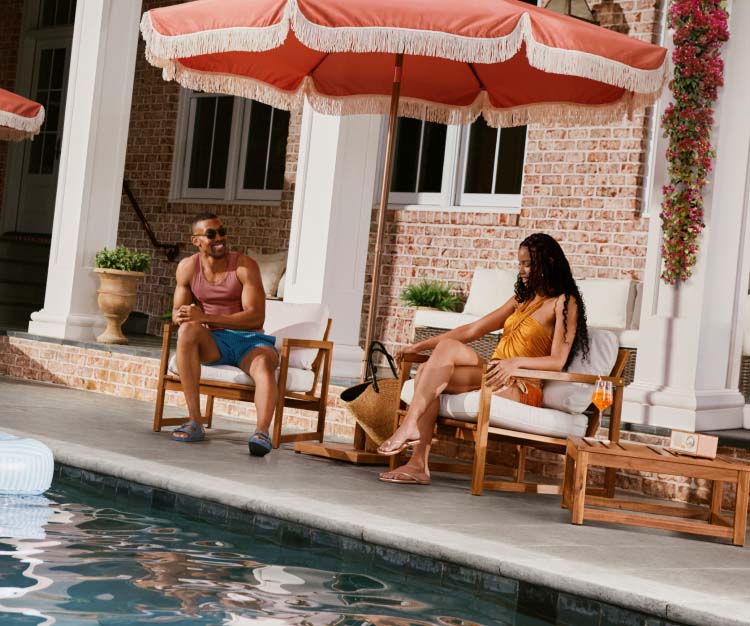 Three people relaxing poolside, with one person floating in the pool.